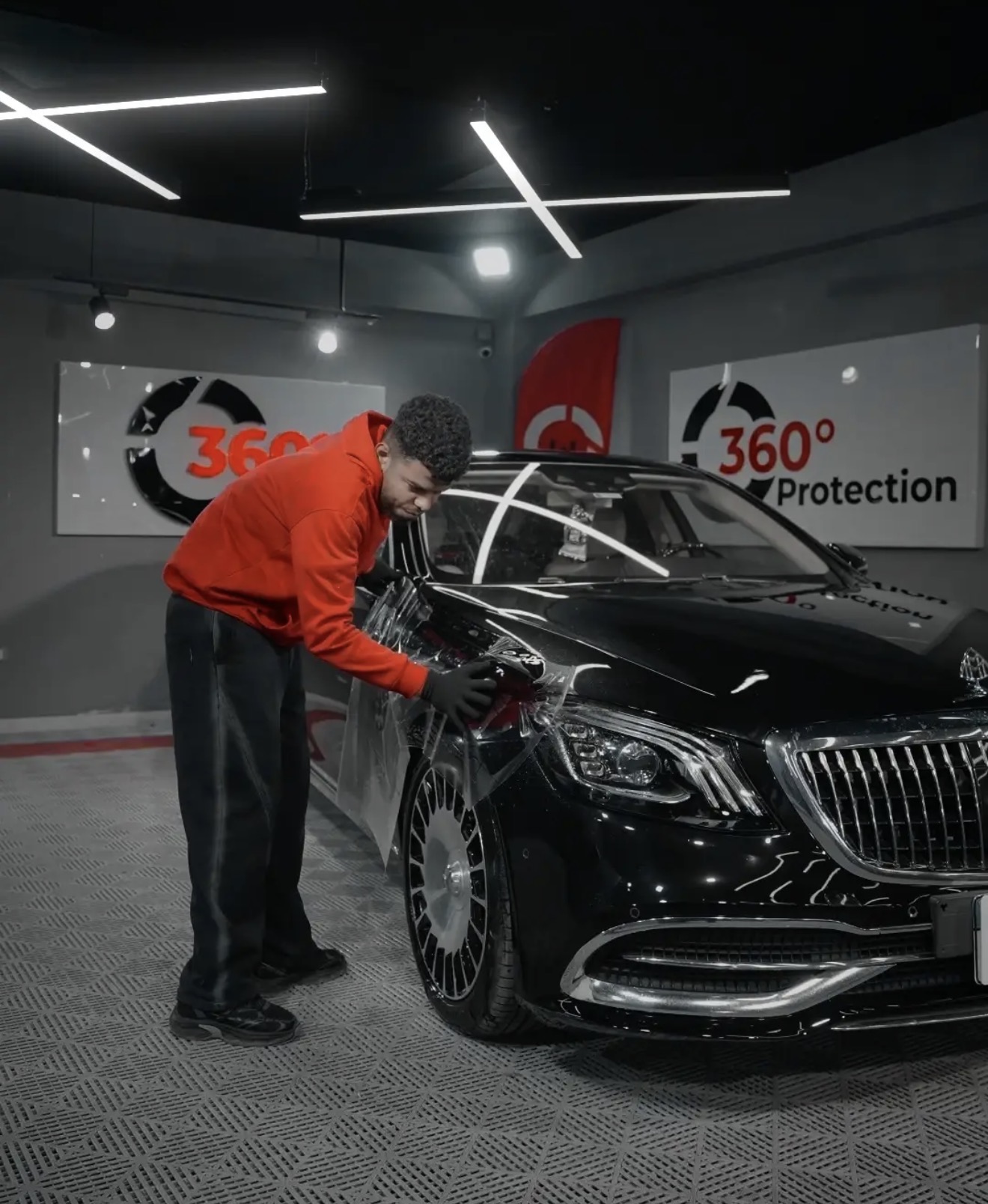 Technician installing PPF on a black Mercedes-Maybach