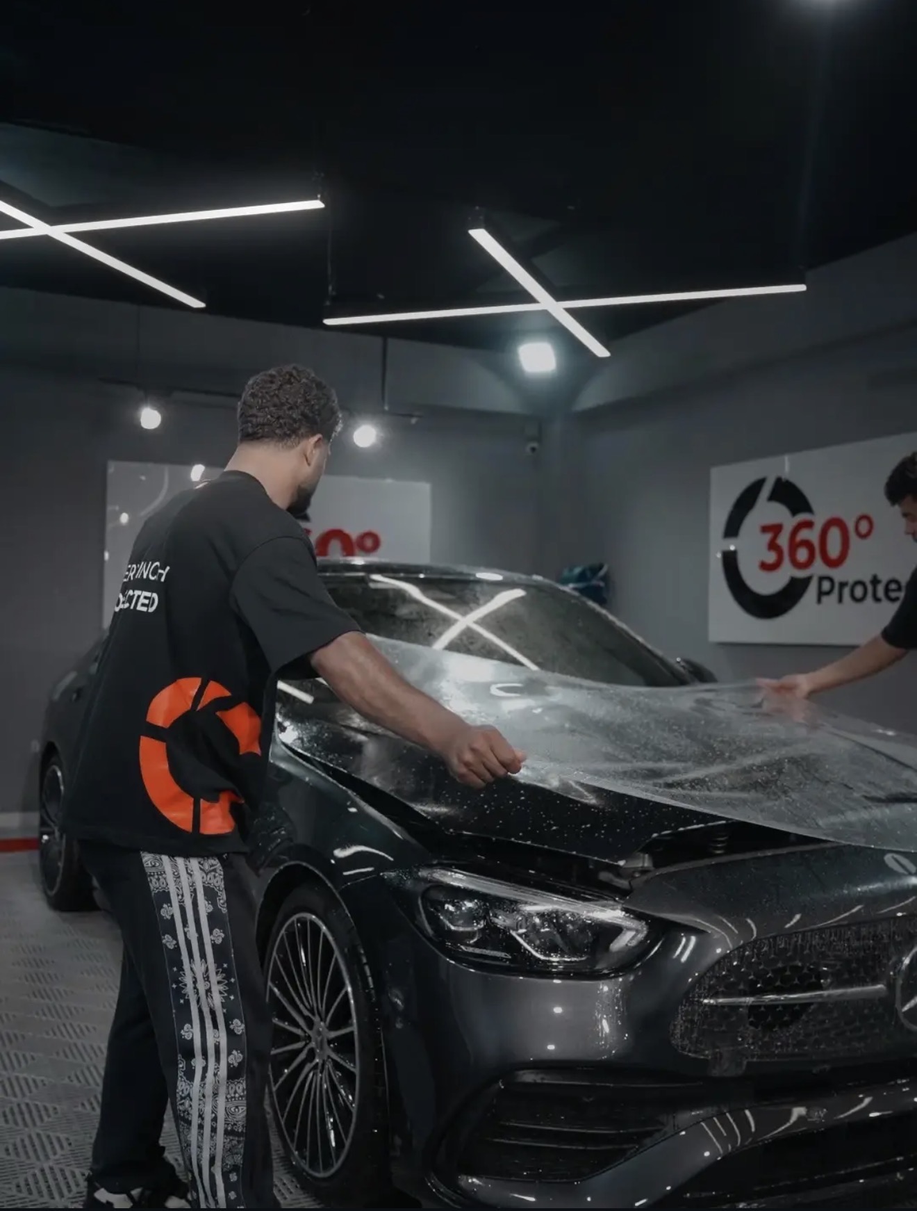 Two installers laying PPF over a Mercedes bonnet